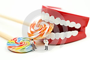 Miniature people : Dentist examining a patient`s teeth with patient and sweet lollipops,healthcare medical concept