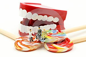 Miniature people : Dentist examining a patient`s teeth with patient and sweet lollipops,healthcare medical concept