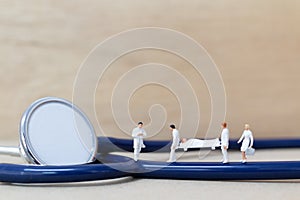 Miniature people : Doctor with nurse carry the patient on a stretcher