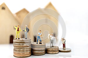Miniature people: Elderly person standing on coins stack with home.