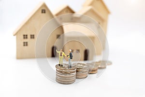 Miniature people: Elderly person standing on coins stack with home, Retirement concept