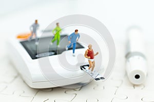 Miniature people exercise running on glucose meter with lancet. Image use for medicine, diabetes, health care concept photo