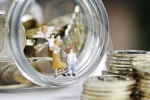 Miniature People : Family are standing on the glass jar full with coins use as saving , insurance and plan for the future