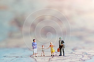 Miniature people: Family walking hand in hand with on world map