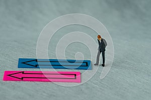 Miniature people figure as businessman thinking with the arrow o