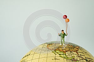 Miniature people figure happy kid / boy holding balloons standing on united states of america map on globe as world climate chang