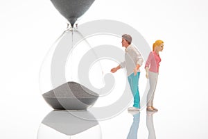 miniature people. figures of a man and a woman near the hourglass on a white background. time to talk. communication and