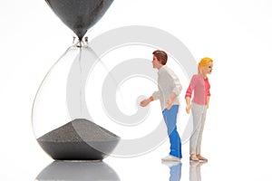 miniature people. figures of a man and a woman near the hourglass on a white background. time to talk. communication and