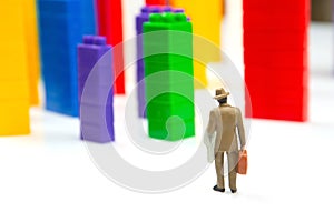 Miniature people. figures of people stand near the colored blocks of a plastic constructor on a white background in the form of