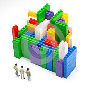 Miniature people. figures of people stand near the colored blocks of a plastic constructor on a white background in the form of