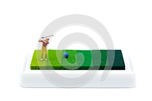 Miniature people : Golfer playing on green background.