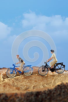 Miniature people: A group of cyclists enjoy rolling on a country road,