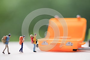 Miniature people : Group of travelers with orange suitcase.