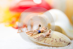 Miniature people : Group travelers sunbathing on shells at the beach . Image use for business travel concept