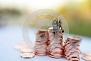 Miniature people: Happy old people sitting on coins stack, Retirement  and Life insurance Concept.