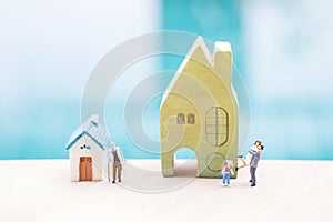 Miniature people with house model over blurred background, family house and retirment home