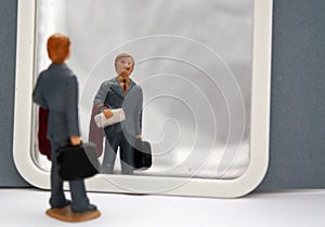 Miniature people male businessman looking himself in the mirror