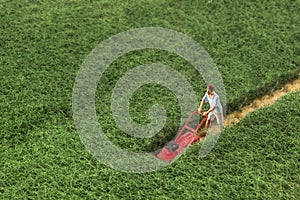 Miniature people: a man is mowing his lawn