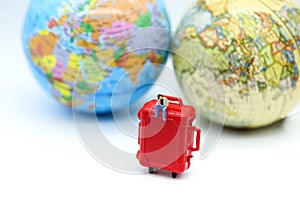 Miniature people : man sitting on red suitcase with mini global