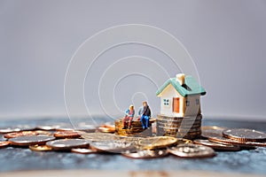 Miniature people, man and woman sitting on stack coins using as business and life success concept