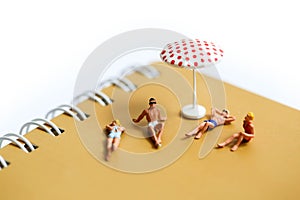 Miniature people : man and woman sunbathing relaxing on beach, o