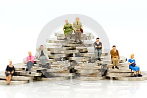 Miniature people, Old couple figure sitting on top of stack coins using as background retirement planning, Life insurance concept.