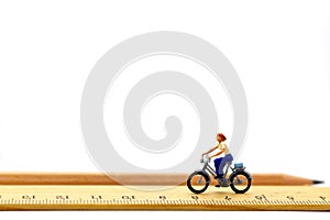 Miniature people ride bicycles on wooden ruler photo