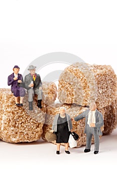 Miniature people: seniors, in front, cubes of brown sugar.