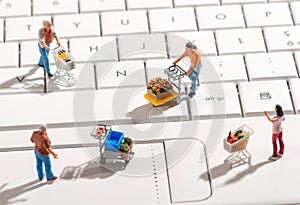 Miniature people with shopping carts on a keyboard