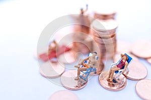 Miniature people sitting on beach sunbath seats and  coins stack.