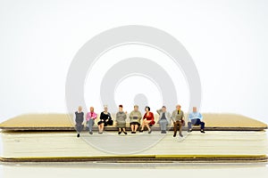 Miniature people sitting on a book. Image use for background education, business concept