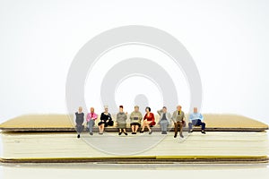 Miniature people sitting on a book. Image use for background education, business concept photo