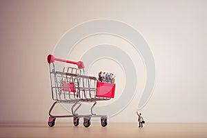 Miniature people sitting on a giant shopping cart. Saving and sh