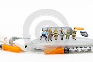 Miniature people sitting on glucose meter with lancet. Image use photo