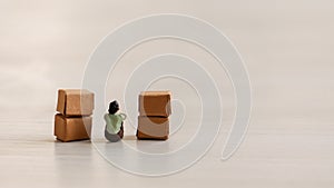 A miniature people sitting in a pile of cardboard boxes.