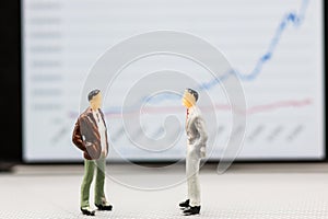 Miniature people : small figures businessmen stand with graph on