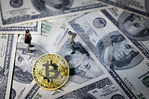 Miniature people small figures businessmen standing and talk about business between Golden bitcoin on one hundred dollar banknotes