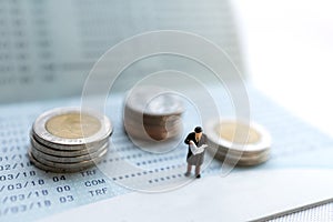 Miniature people stand on the bank passbook and coins stack, Retirement planning and life insurance concepts
