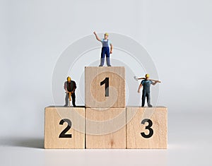 Miniature people standing on top of the ranked wooden blocks.