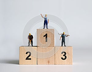 Miniature people standing on top of the ranked wooden blocks. photo