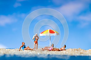 Miniature people sunbathing on The beach with blue sky background