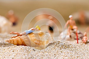 Miniature people in swimsuit on the beach