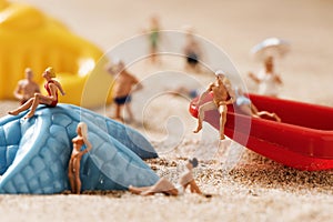 Miniature people in swimsuit on the beach