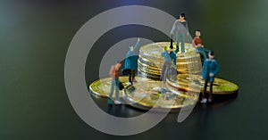 Miniature people teamworks, small model human figure standing and sitting on golden Bitcoins stack with copyspace for your text.