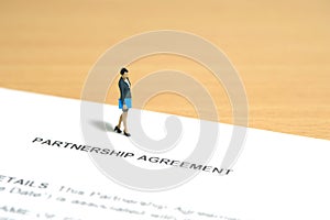 Miniature people toy figure photography. Business partner contract sign concept. A businesswoman walking above partnership