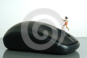 Miniature people toy figure photography. Creative concept. A girl runner jogging above black mouse,  on white background