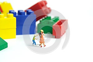 Miniature people toy figure photography. Fun learning concept. Kids playing building block together. Isolated on white background