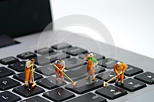 Miniature people toy figure photography. Group of sweeper workers cleaning notebook laptop keyboard using broom, brush. Isolated