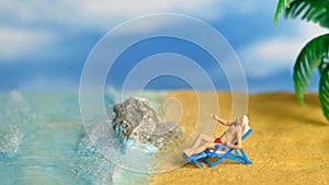 Miniature people toy figure photography. A Men relaxing on beach chair when daylight at seaside