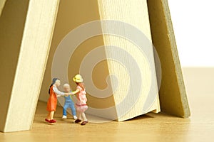 Miniature people toy figure photography. Play tent at home. Kids playing together bellow book